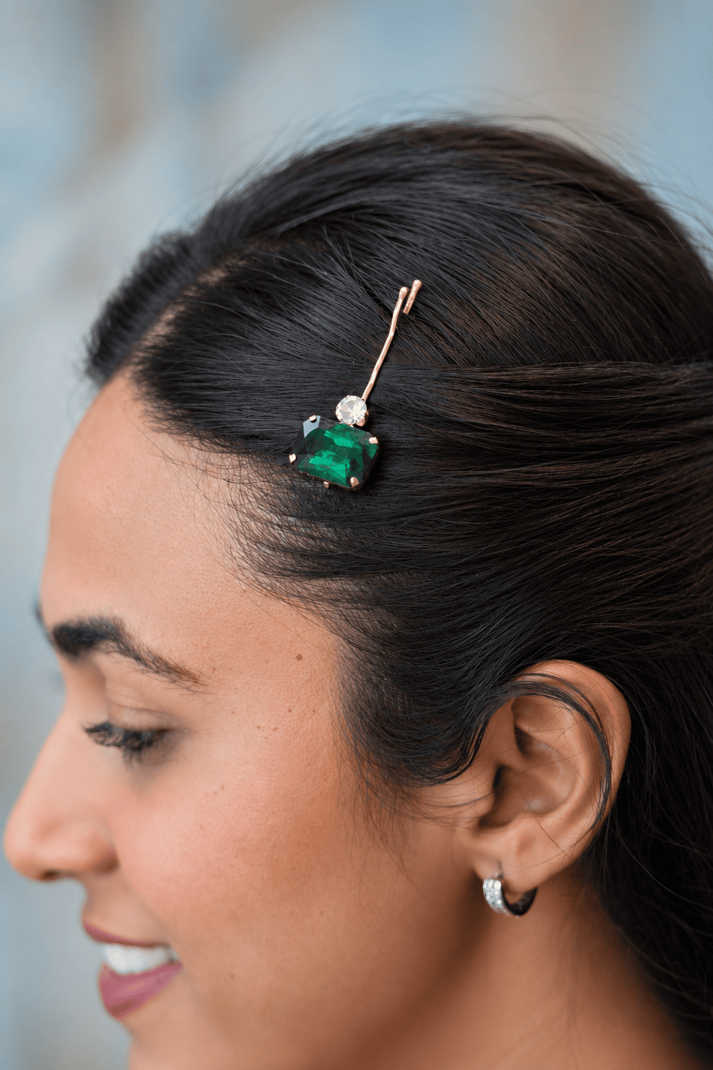 Close up side view of model hair styled with a single emerald green gemstone hair pin by IQ Edit.