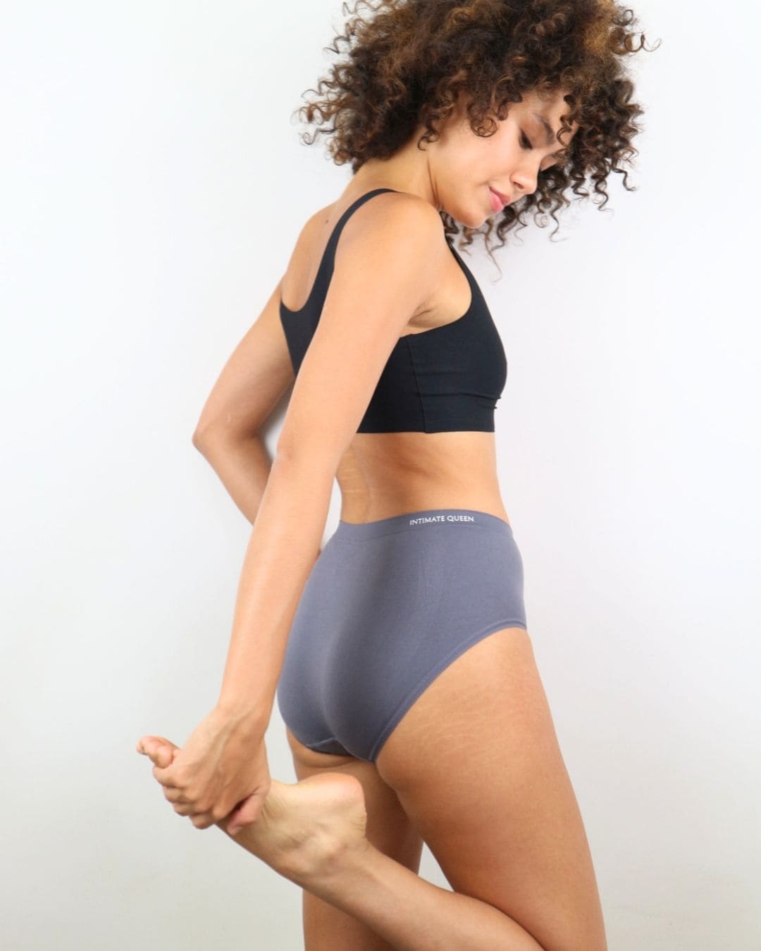 Woman wearing a black seamless bra and Charcoal gray underwear on a white background
