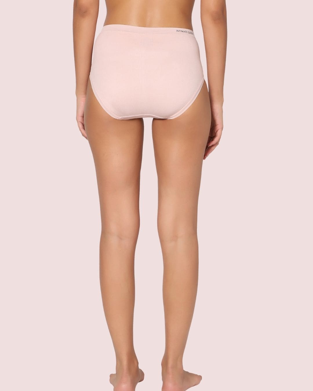 Person wearing a light pink high-waisted underwear on a plain background