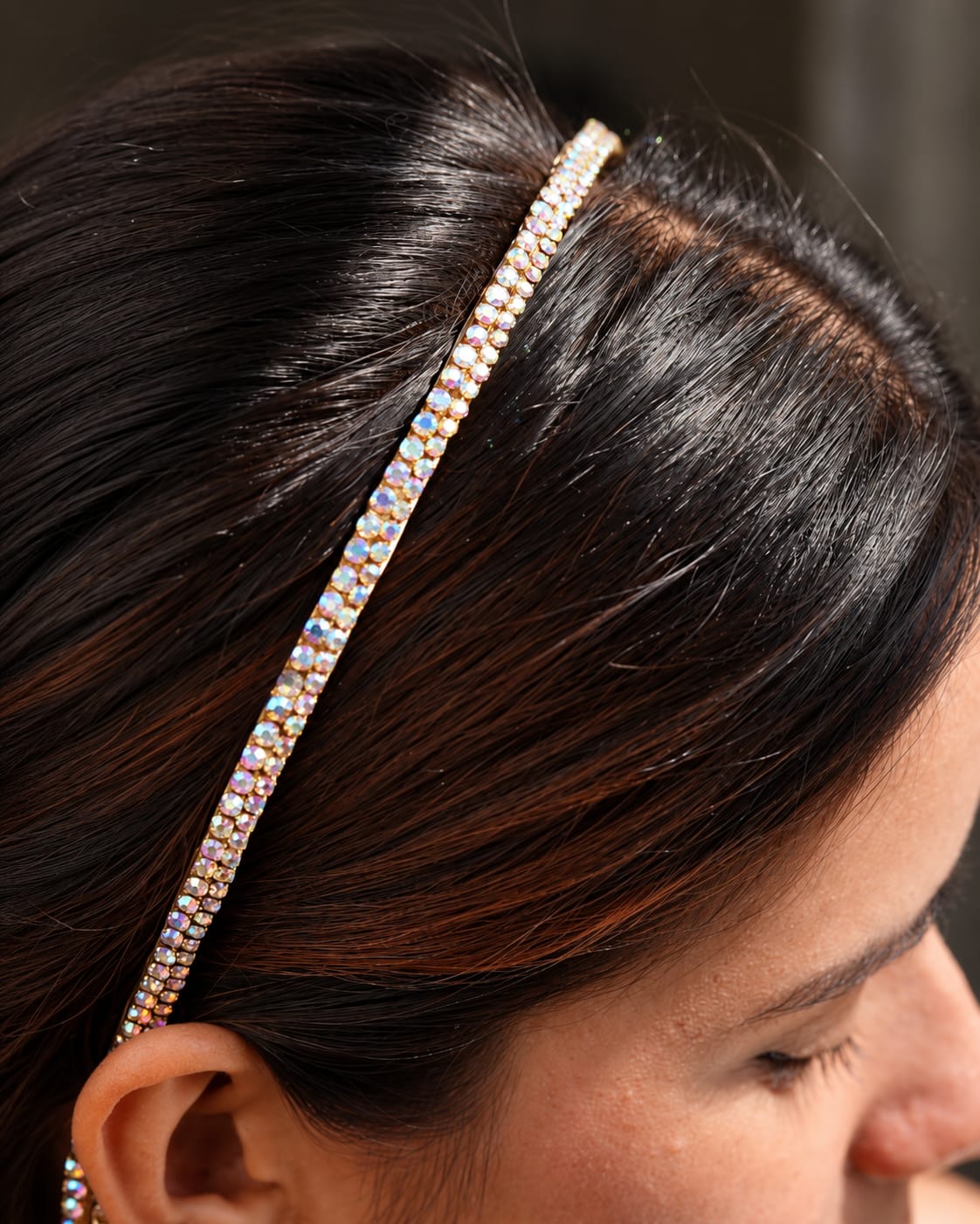 Gold-tone crystal tassel headband with iridescent rhinestones worn in dark hair