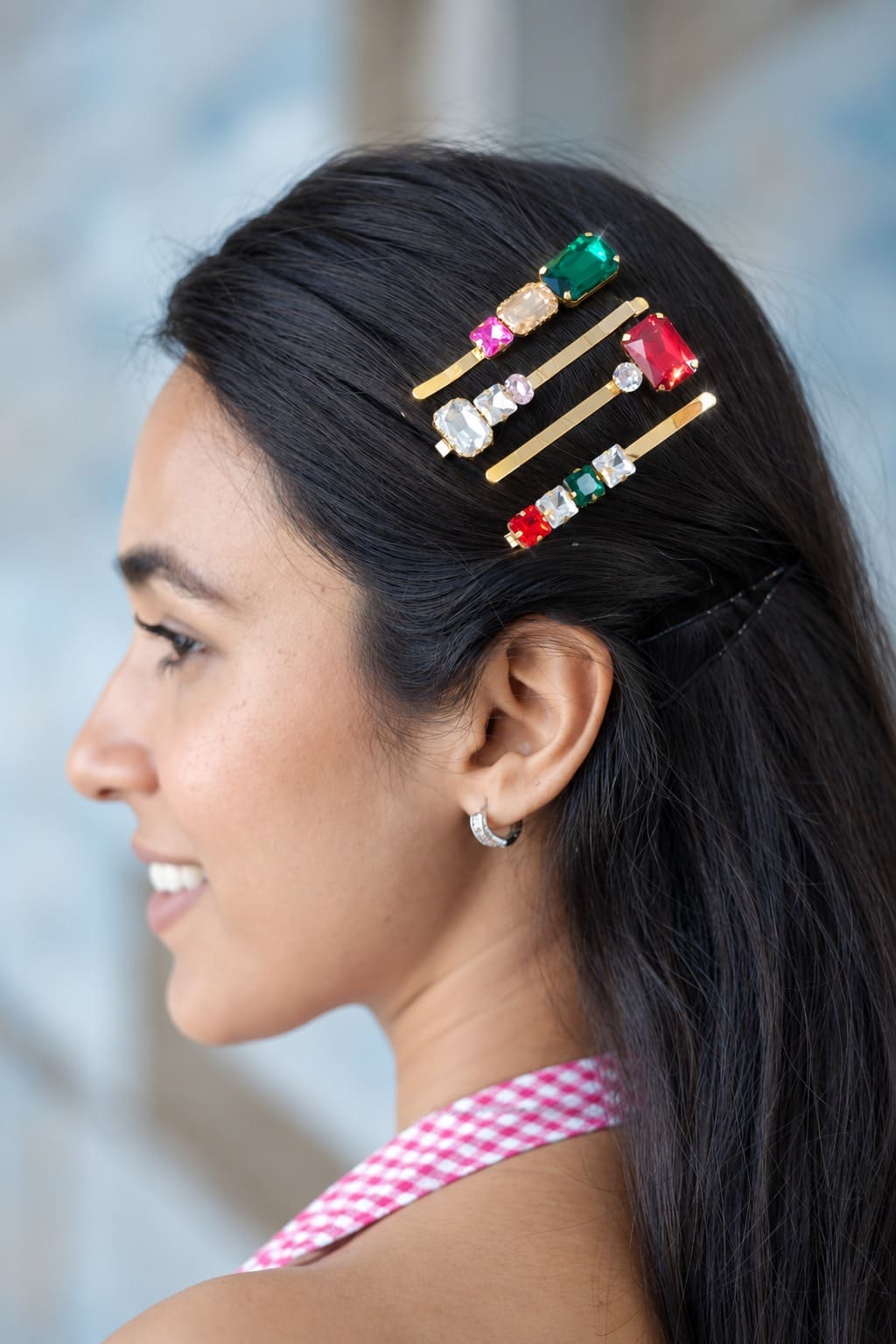 A set of four gold-tone crystal hairpins with green, red, pink and clear gemstones styled on a woman.