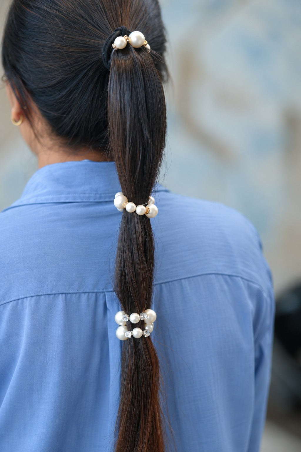 Woman wearing pearl hair ties along a long ponytail