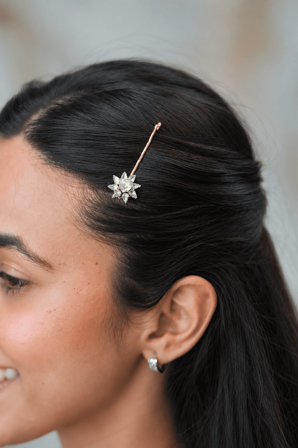 Close-up front profile of a model styling a side part with a single vintage-inspired crystal flower hair pin.