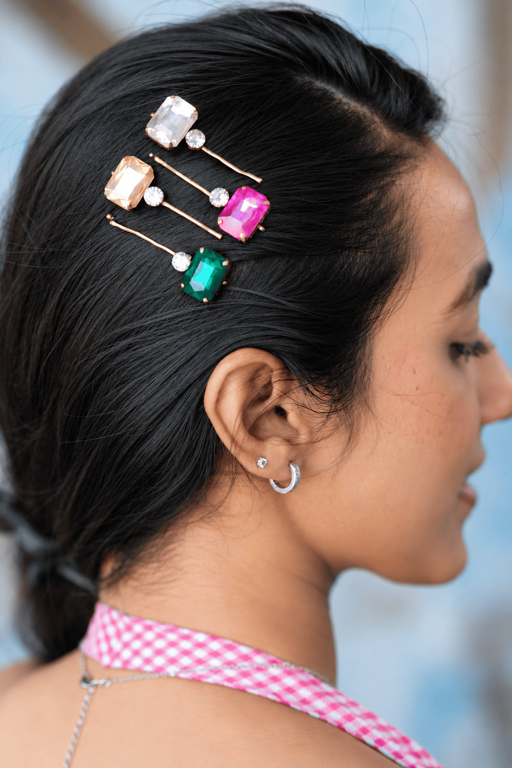 Side view of model wearing three stacked IQ Edit crystal hair pins in clear, champagne, emerald green and pink